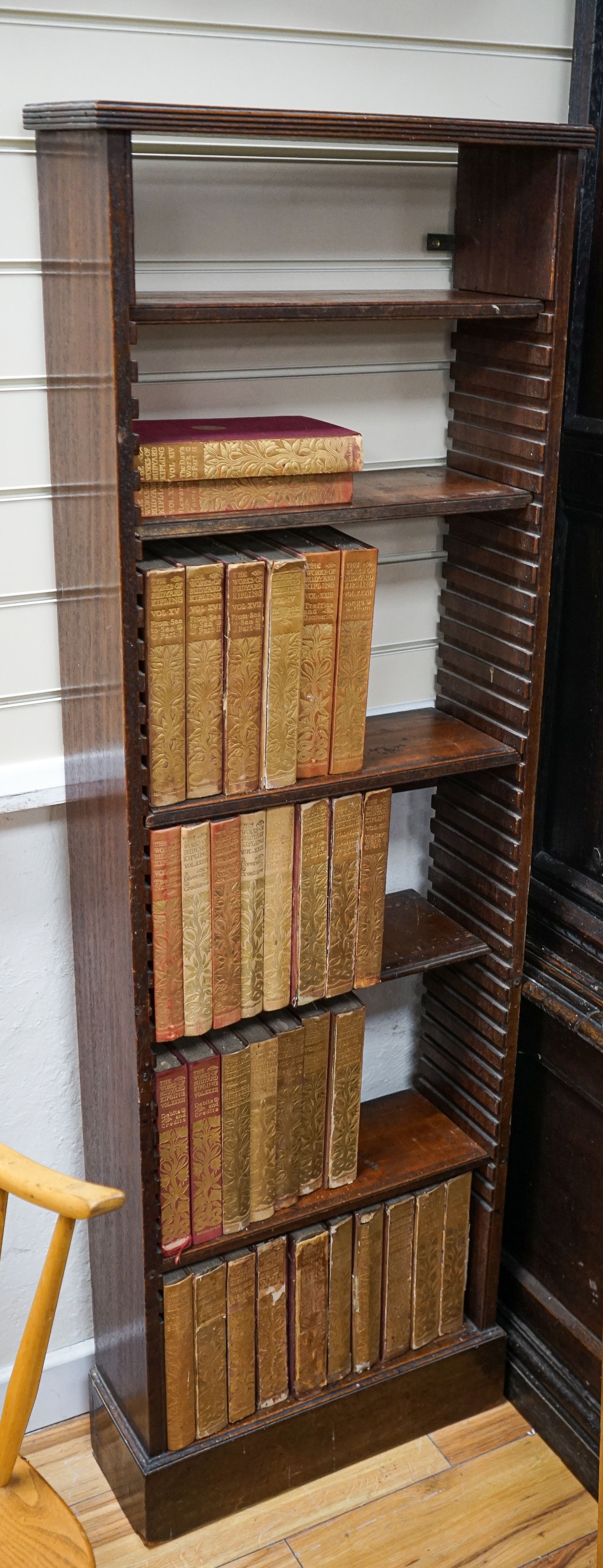 A Georgian mahogany wall-mounted narrow bookshelf, width 48cm, depth 18cm, height 147cm, containing a limited edition Works of Rudyard Kipling in 33 volumes, published 1900